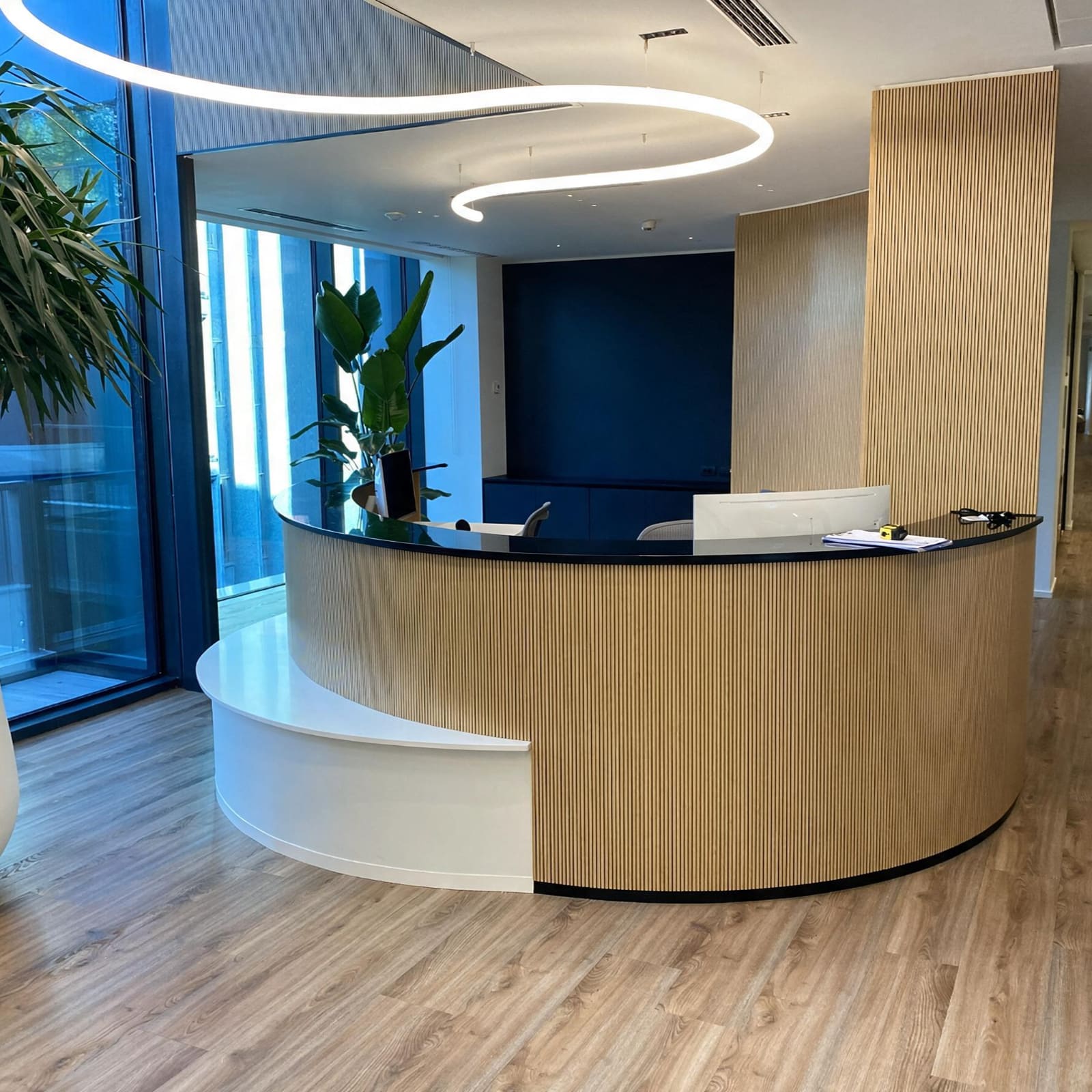 Reception curva in Corian e legno dogato — Milano